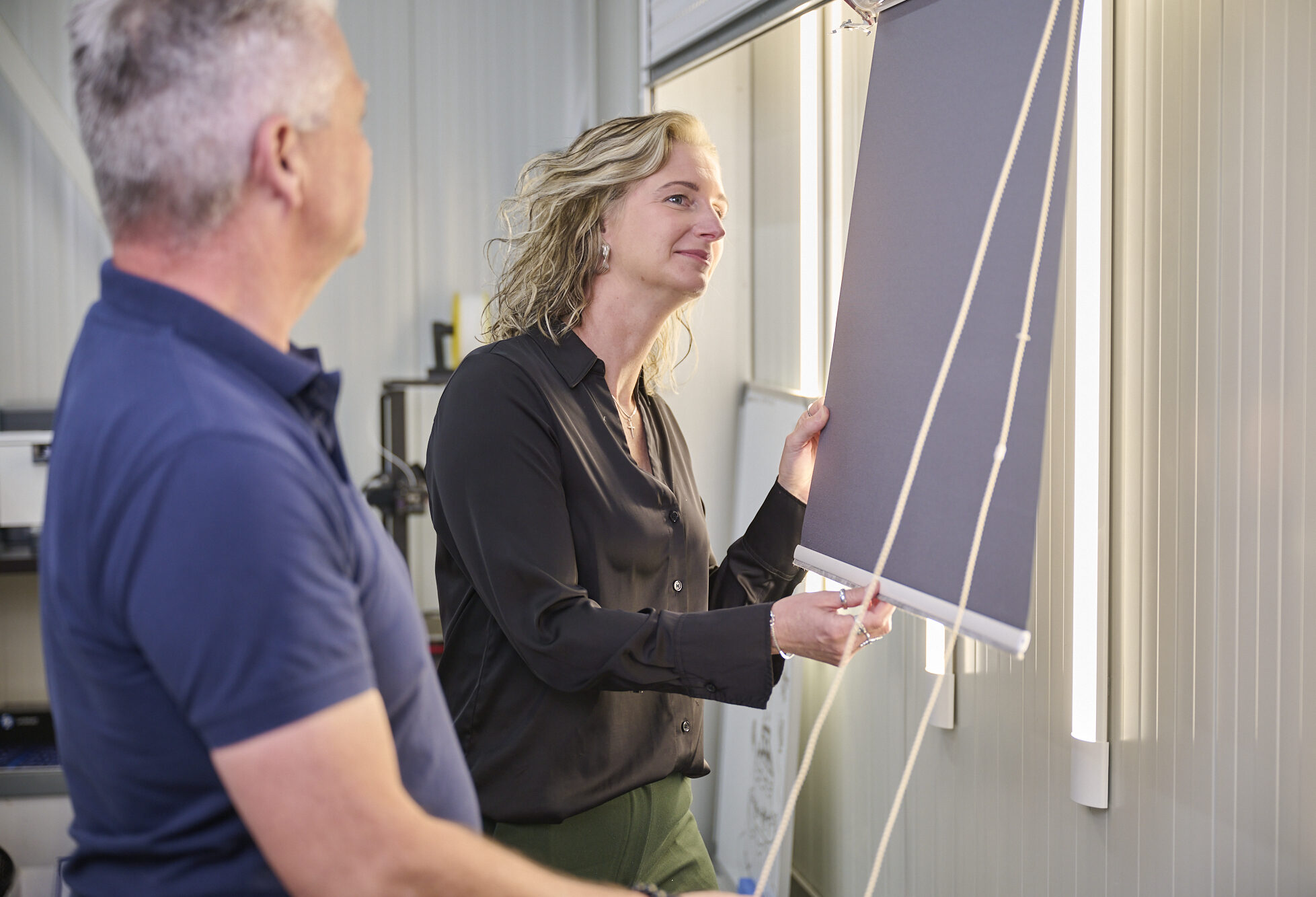 Klant bekijkt rolgordijn in de showroom van Rol Techniek Benelux.