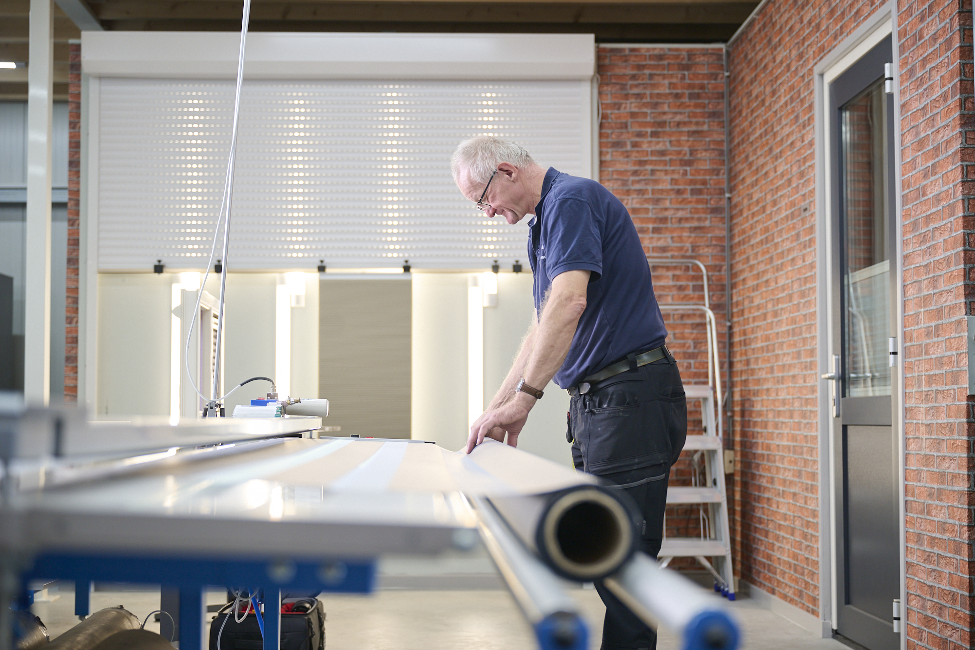 Werknemer in de werkruimte bezig met het maken van een rolgordijn bij Rol Techniek Benelux.